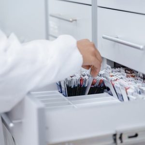 A person wearing a lab coat organizing files in a medical laboratory drawer.